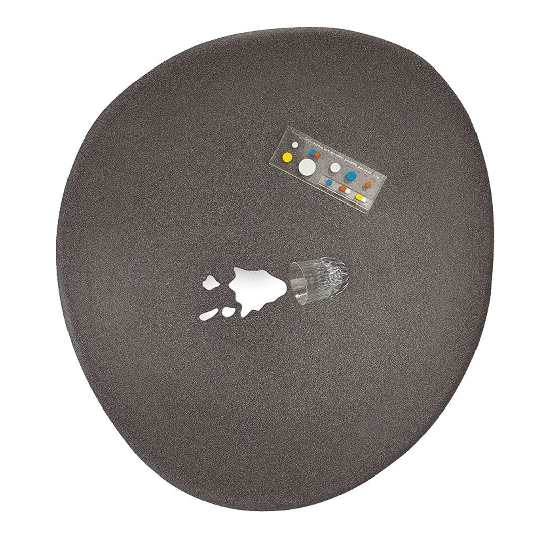 Textured dark gray oval surface with subtle patterns and a remote control featuring colorful buttons.