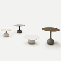 Modern round coffee tables in cream, white, and dark brown with smooth finishes and minimalist designs.