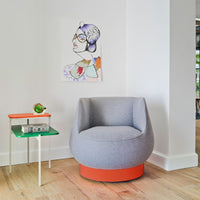 Gray upholstered chair with orange base, paired with colorful green and orange table. Modern, vibrant design.
