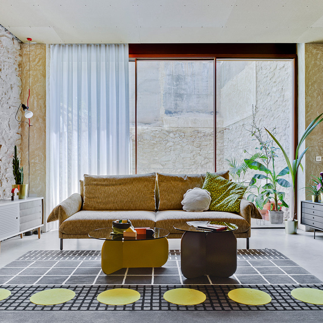 Cozy living room featuring a brown sofa, green accents, a black and white checkered rug, and yellow circular decor.