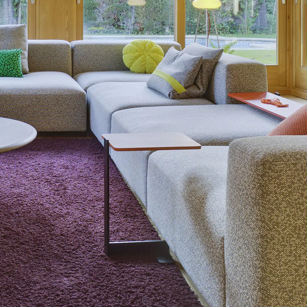 Gray textured sofa with lime green and teal accents, set on a purple rug in a bright, modern living space.
