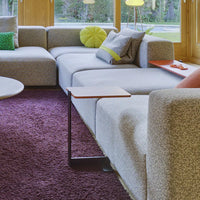 Gray textured sofa with lime green and teal accents, set on a purple rug in a bright, modern living space.