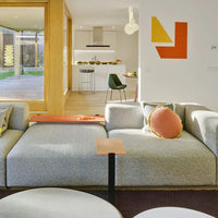 Light gray textured sofa with orange and peach cushions, accented by vibrant yellow and red geometric wall art.