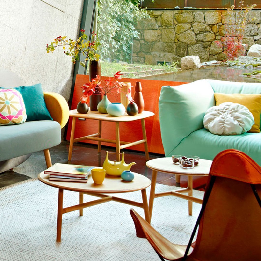 Brightly colored furniture featuring turquoise, orange, and pastel accents with geometric patterns and wooden tables.