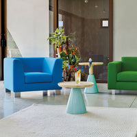 Vibrant blue and green armchairs with a round light blue table, set against a modern neutral backdrop.