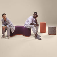Purple curved bench, orange and gray cylindrical stools, set against a neutral background. Modern, textured design elements.