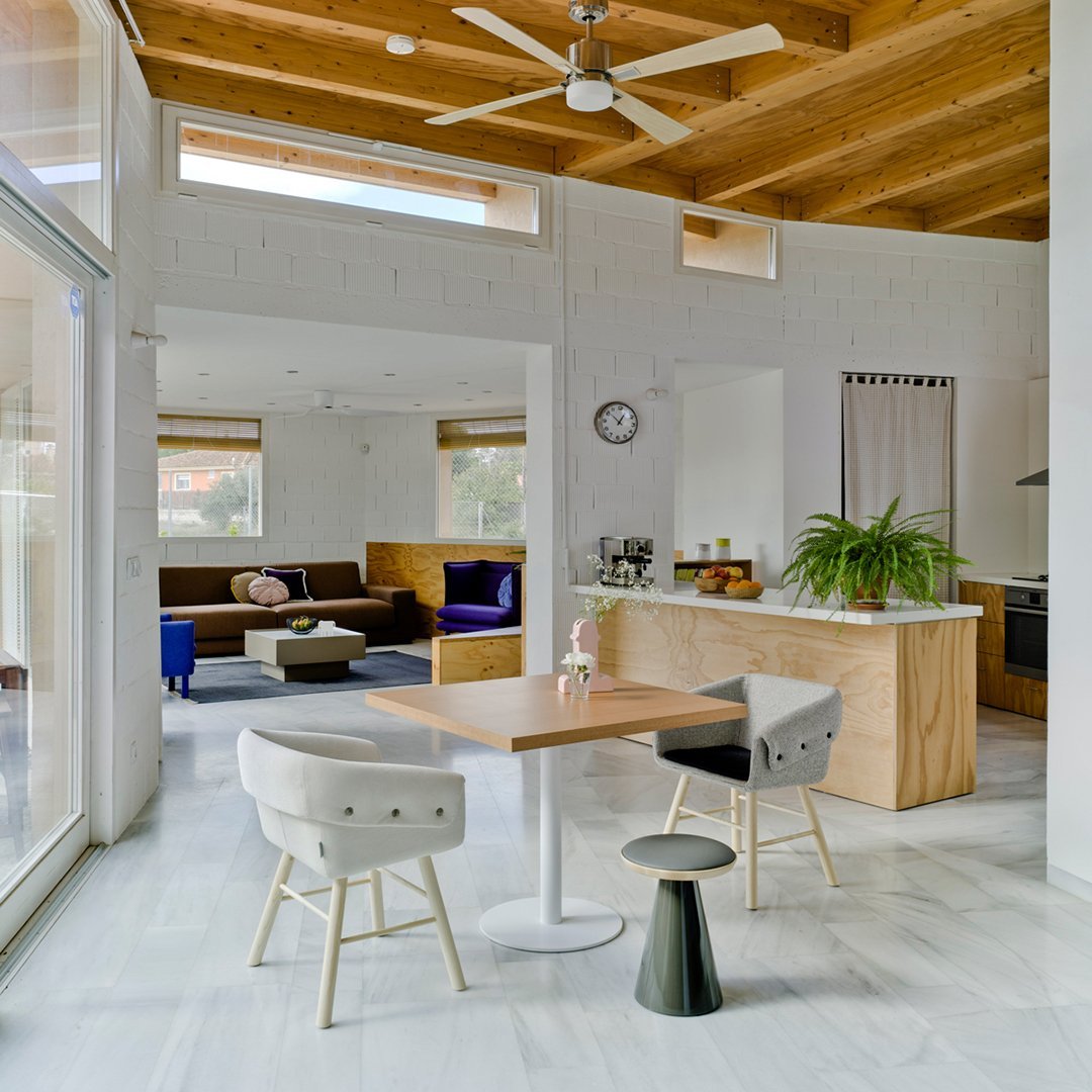 Modern interior with a mix of white, natural wood, and black accents, featuring bold blue and purple furniture patterns.
