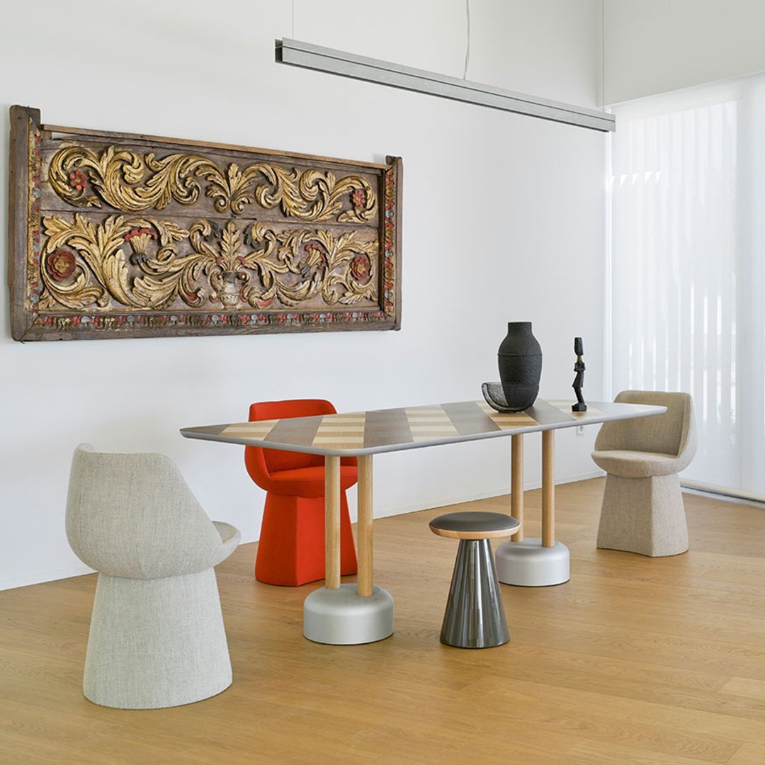 "Modern dining set with neutral gray, cream, and vibrant orange accents against a warm wooden floor."