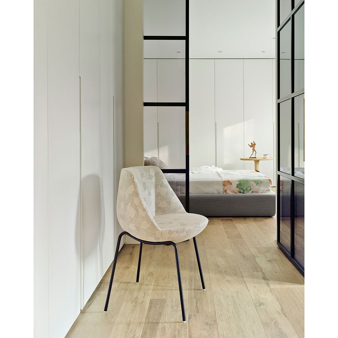Neutral beige chair with soft texture, complemented by black legs, in a contemporary room setting with light wood flooring.