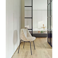 Neutral beige chair with soft texture, complemented by black legs, in a contemporary room setting with light wood flooring.