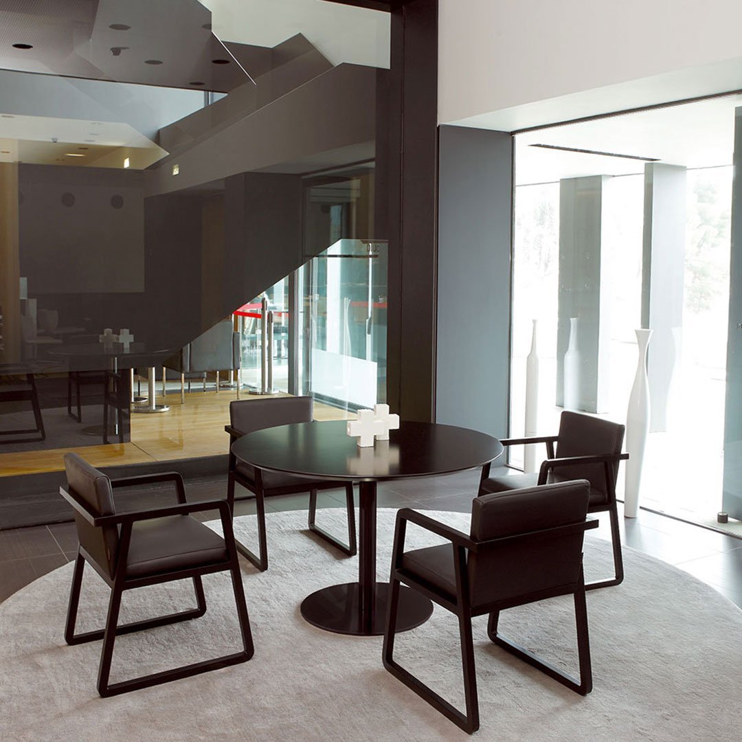 Modern black dining set with sleek chairs and a round table, set against a light gray carpet in a stylish interior.