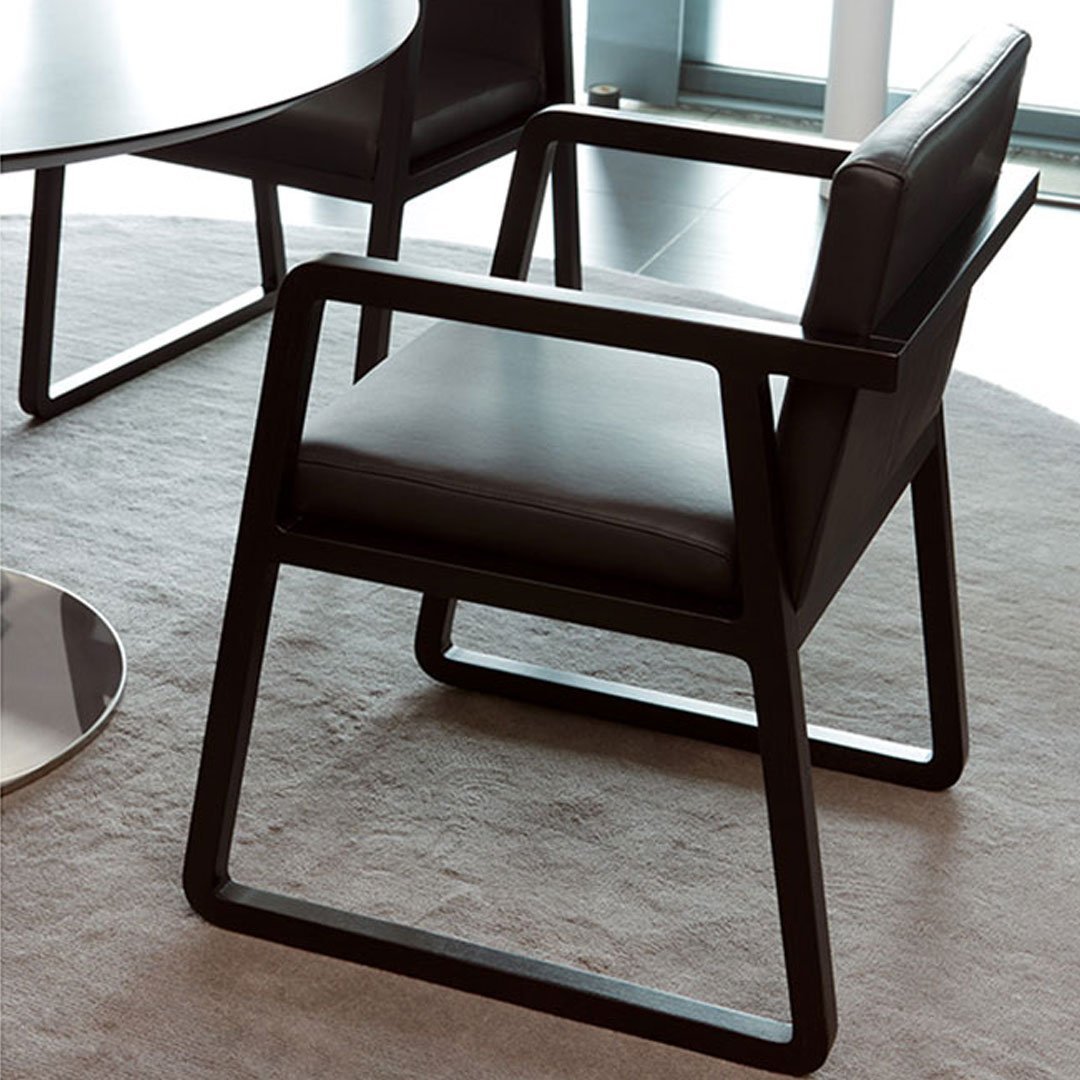 Black modern chair with a sleek, minimalist design, resting on a light gray carpet.
