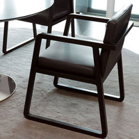 Black modern chair with a sleek, minimalist design, resting on a light gray carpet.