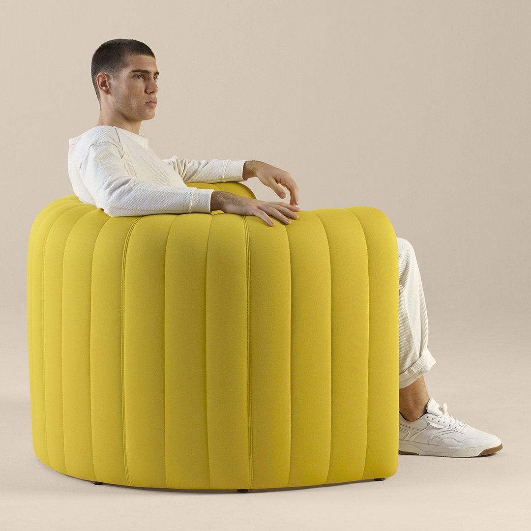 Bright yellow rounded chair with vertical ribbed pattern, set against a neutral background. Modern and stylish design.