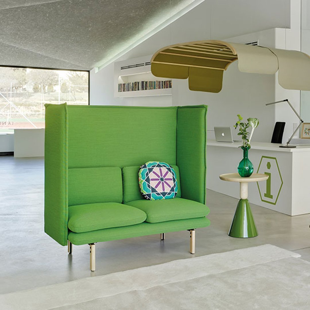 Vibrant green two-seater sofa with a colorful patterned cushion, accentuated by modern furnishings in a bright setting.