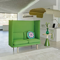 Vibrant green two-seater sofa with a colorful patterned cushion, accentuated by modern furnishings in a bright setting.