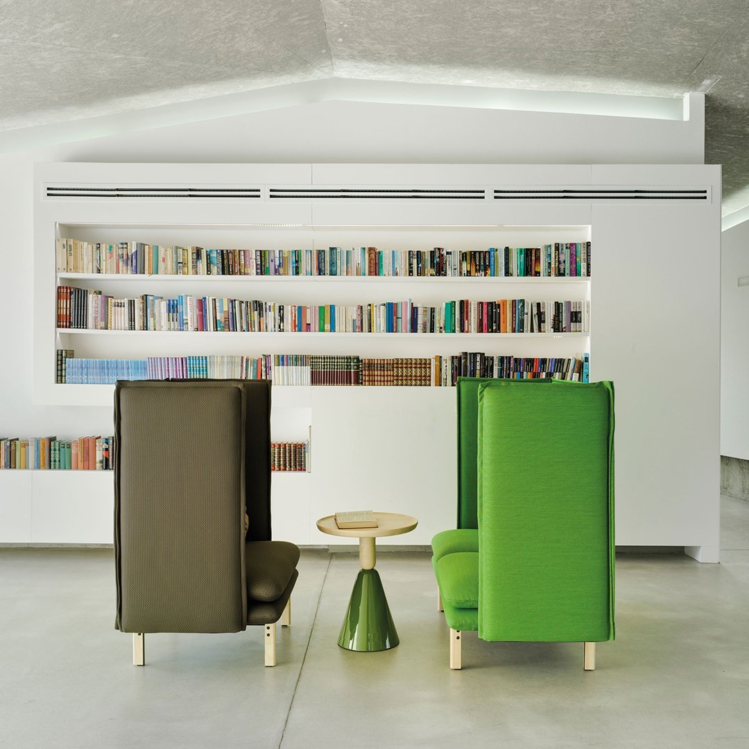 Green and brown upholstered chairs with a modern design and a round, green accent table in a sleek, minimalistic setting.