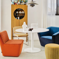 Vibrant orange, blue, and gray chairs with textured patterns around a sleek white table in a stylish interior setting.