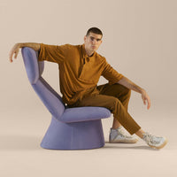 Lavender chair with smooth curves, paired with a rich brown outfit, soft textures, and neutral backdrop. Stylish and modern.