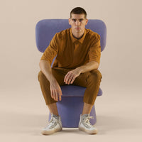 Men's outfit in warm brown tones, featuring a solid color polo and matching trousers, paired with stylish white sneakers.