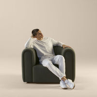 Green upholstered armchair with a smooth, modern design, paired with a neutral beige background.