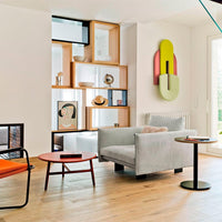 Light gray sofa with colorful geometric wall art, warm wood tones, and bold accent colors in modern interior design.