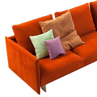 Orange velvet sofa with textured brown, green, lavender, and pink accent pillows. Stylish modern home decor.