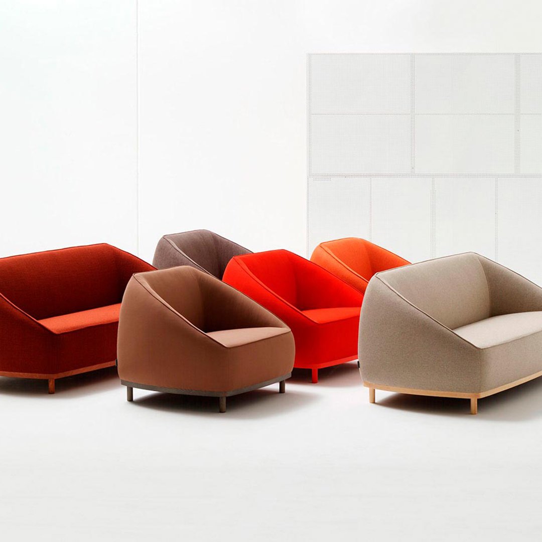 Five modern sofas in vibrant hues of red, orange, brown, and beige, featuring smooth, curved shapes and plush upholstery.