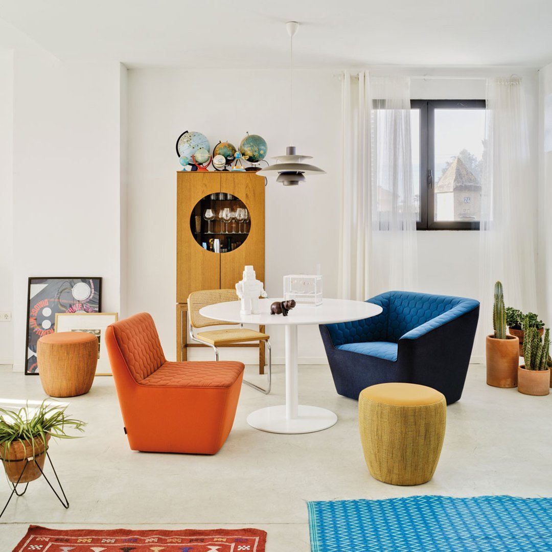 Colorful modern living space featuring orange, blue, and yellow accents with geometric patterns on decor items.