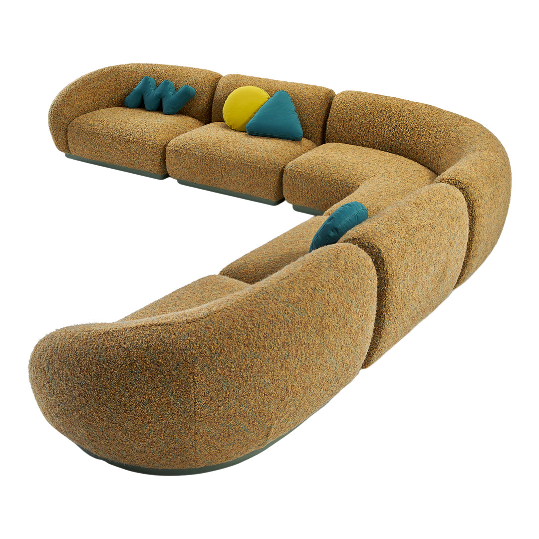 Curved sofa in warm orange fabric with vibrant blue and yellow accent pillows and a textured finish.