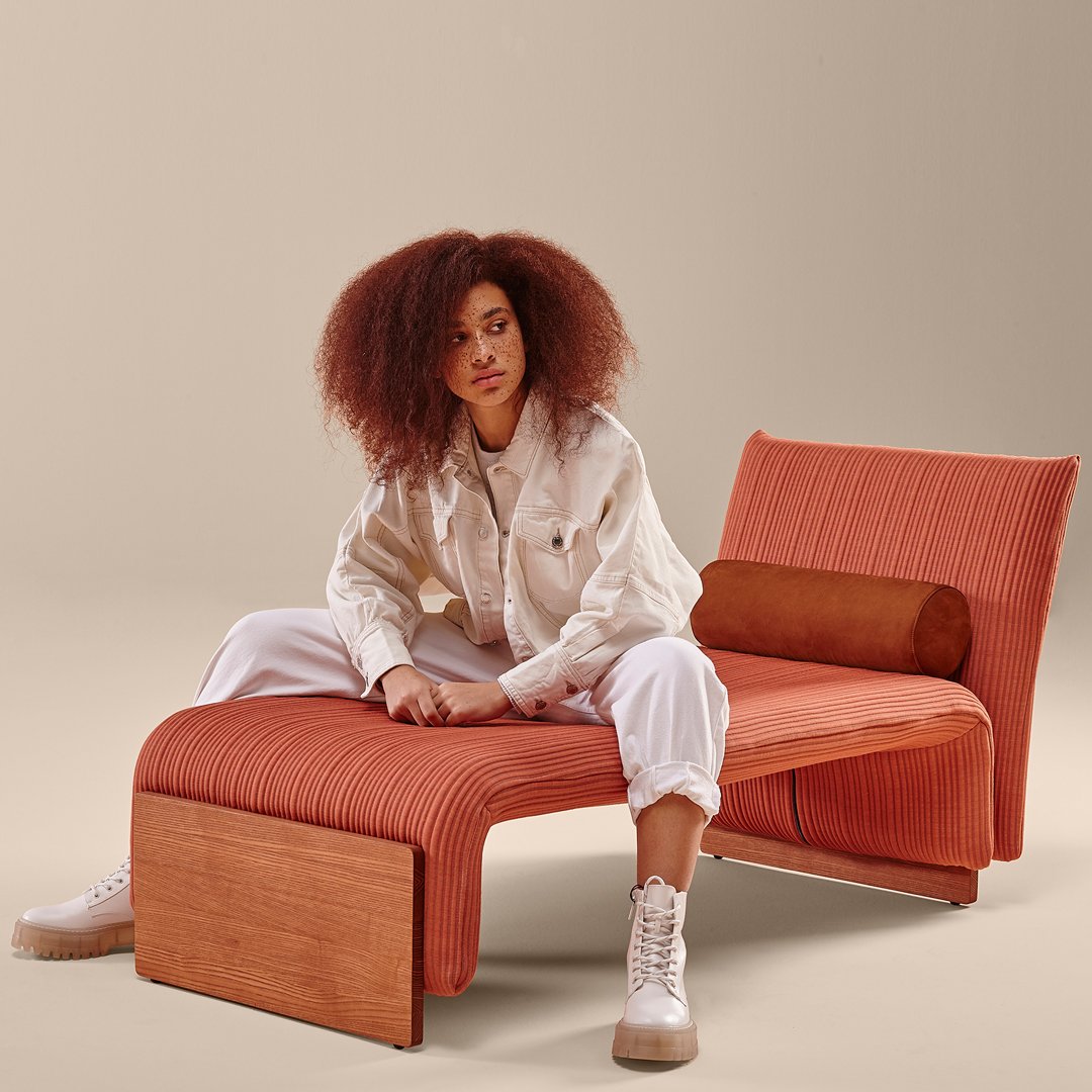 Rust-orange lounge chair with ribbed texture and wooden accents, perfect for modern interiors.