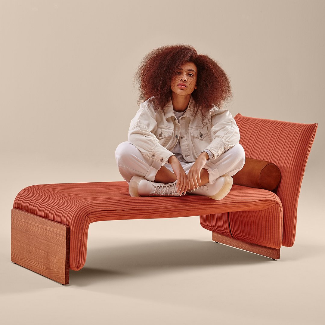 Rust orange lounge chair with textured fabric, featuring smooth wood accents. Stylish modern design for any space.