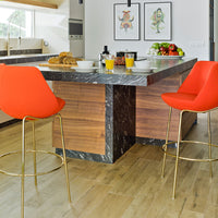 Modern kitchen island with marble top, paired with vibrant orange bar stools and warm wood accents. Clean, bright aesthetic.
