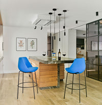 Modern kitchen featuring blue bar stools, wooden island, and sleek black pendant lights against a neutral backdrop.