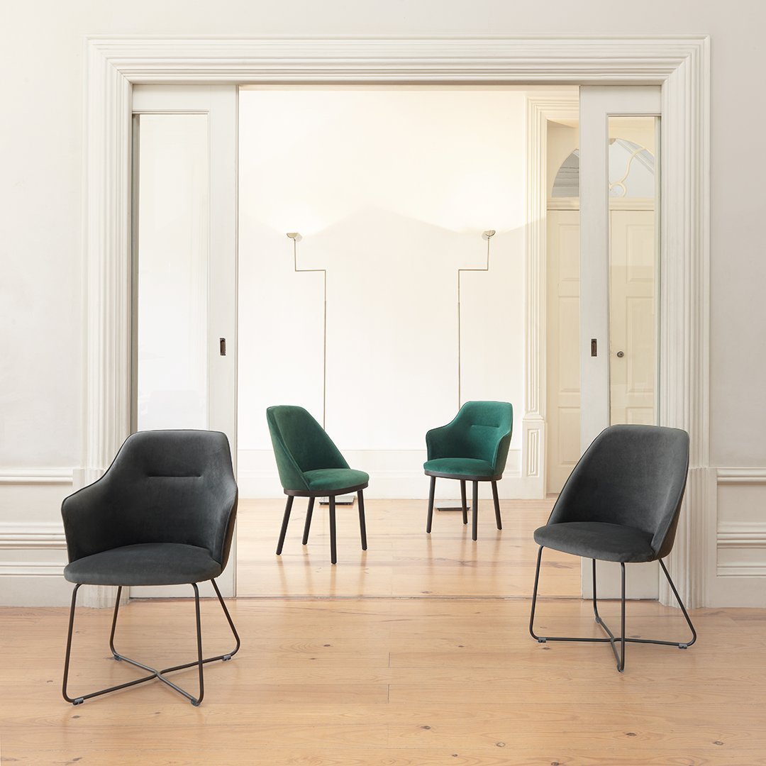 Set of four stylish chairs in dark gray and rich green fabrics, featuring smooth curves and minimalist design.