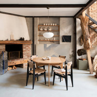 Modern wood dining table with black chairs, featuring natural wood tones and neutral wall textures in a stylish interior.