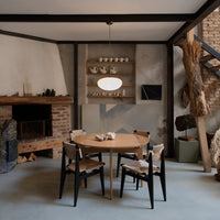 Modern wooden table and black chairs in a neutral-toned room with subtle textures and natural decor accents.