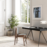 Modern workspace featuring a black desk, soft gray chair, and neutral tones with subtle greenery and natural light.