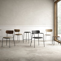 Set of minimalist chairs in black, brown, and light wood hues with sleek metal frames, arranged in a modern space.