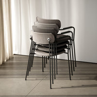 Stacked gray chairs with sleek black metal legs against a light background, showcasing a modern and minimalist design.