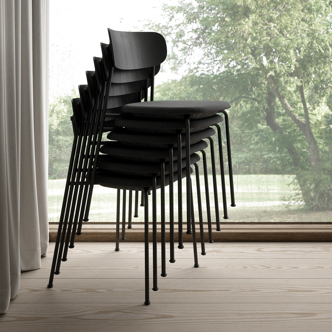 Stack of sleek black chairs with a minimalist design, showcasing a smooth finish against a light wood floor.