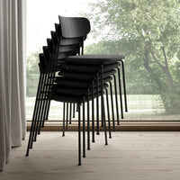 Stack of sleek black chairs with a minimalist design, showcasing a smooth finish against a light wood floor.