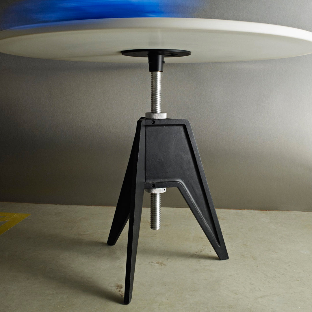 Modern table with a sleek black base and a smooth white top, featuring a subtle blue accent in the background.