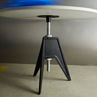 Modern table with a sleek black base and a smooth white top, featuring a subtle blue accent in the background.