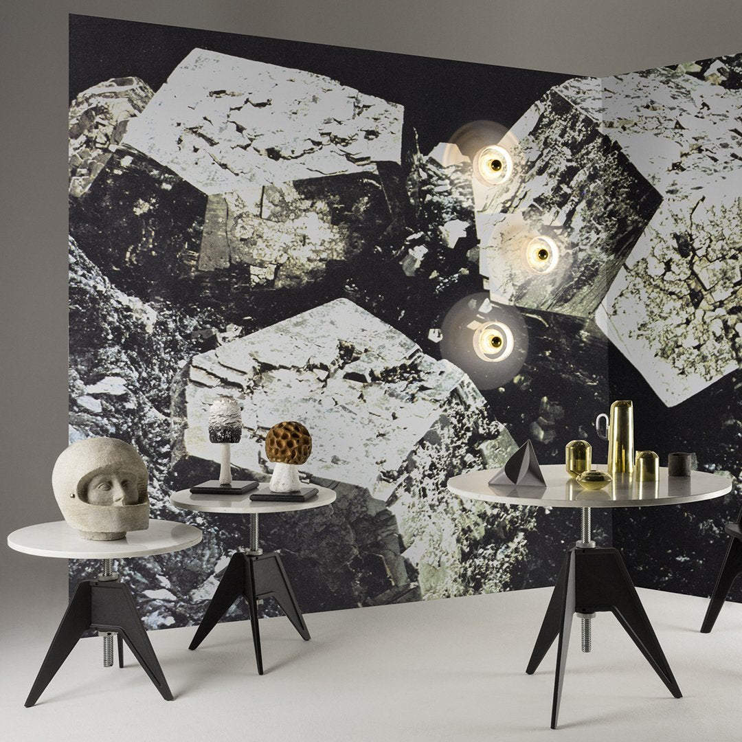 Geometric black and white patterned wall with glossy surfaces and modern table decor in neutral tones.