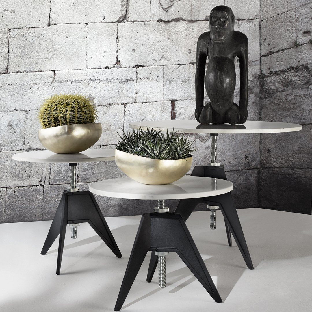 Modern black and white side tables with round tabletops, featuring gold and green decorative planters.