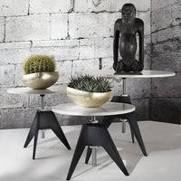 Modern black and white side tables with round tabletops, featuring gold and green decorative planters.