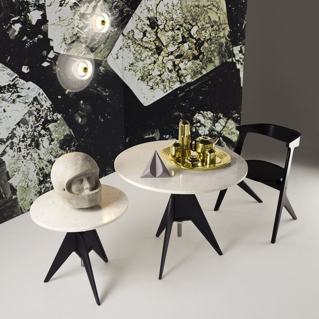 Modern black and white tables with smooth surfaces and geometric patterns against a textured, abstract wallpaper background.
