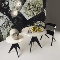 Modern black and white tables with smooth surfaces and geometric patterns against a textured, abstract wallpaper background.