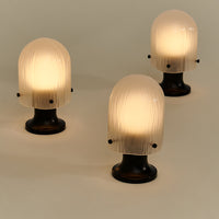 Set of three elegant table lamps featuring textured white glass shades and sleek black bases, creating a modern contrast.